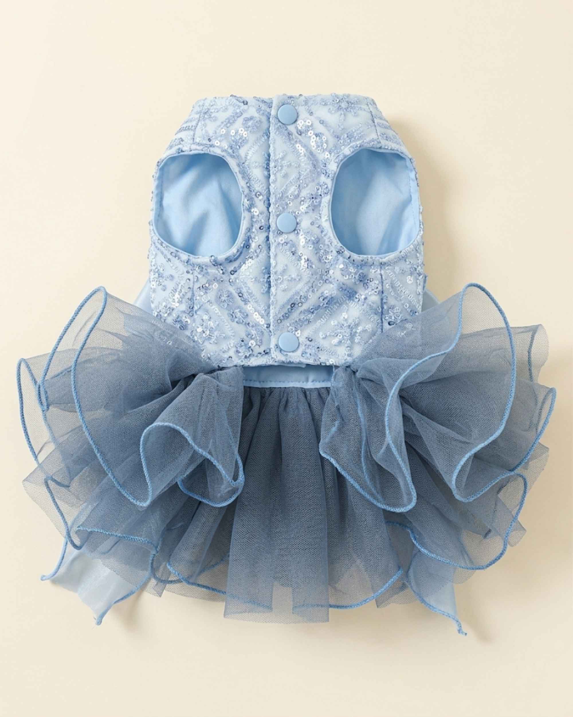 Front closure flat lay of a celestial blue pet dress with two leg openings, three pale blue snap buttons and a layered smoky blue tulle skirt.