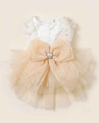 Back flat lay of the champagne tulle pet dress with a white satin bodice, oversized bow and pearl heart ornament