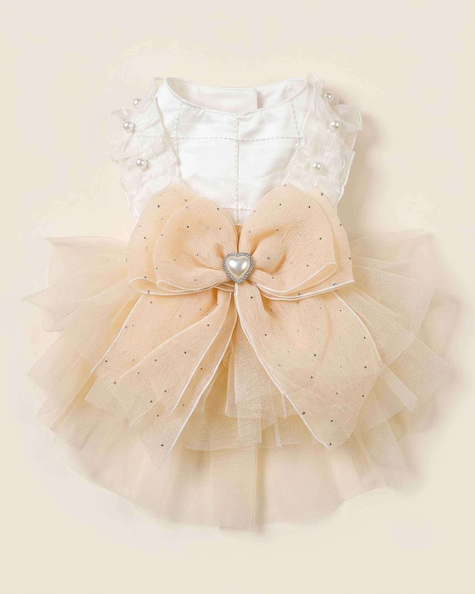 Back flat lay of the champagne tulle pet dress with a white satin bodice, oversized bow and pearl heart ornament