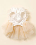 Front flat lay of the pet dress showing its white satin bodice, arm openings, ruffles, snap buttons and champagne tulle skirt