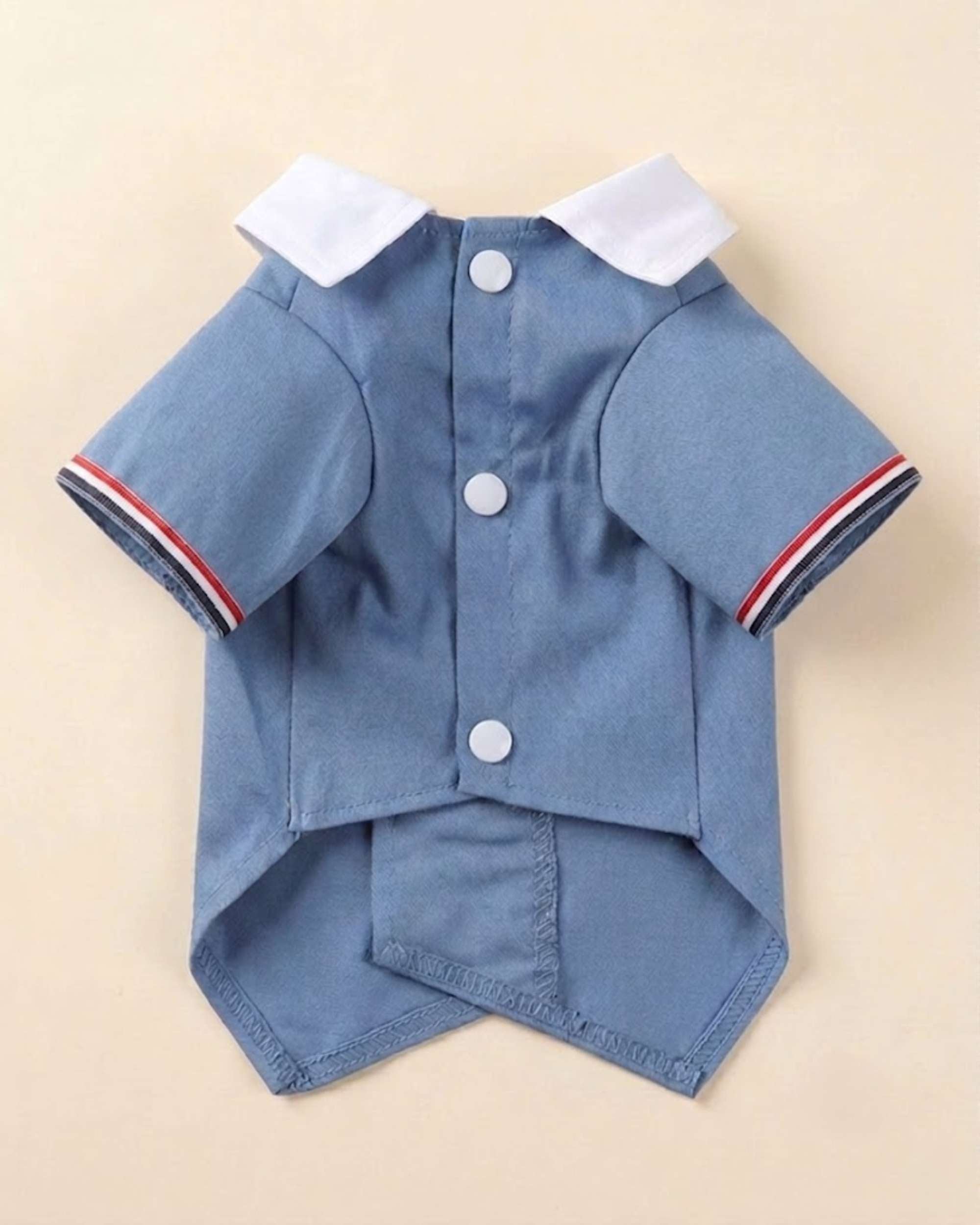 Closure-side flat lay of the Denim Blue Double-Breasted Pet Tuxedo showing three white snap fasteners, white collar and striped sleeve trim.