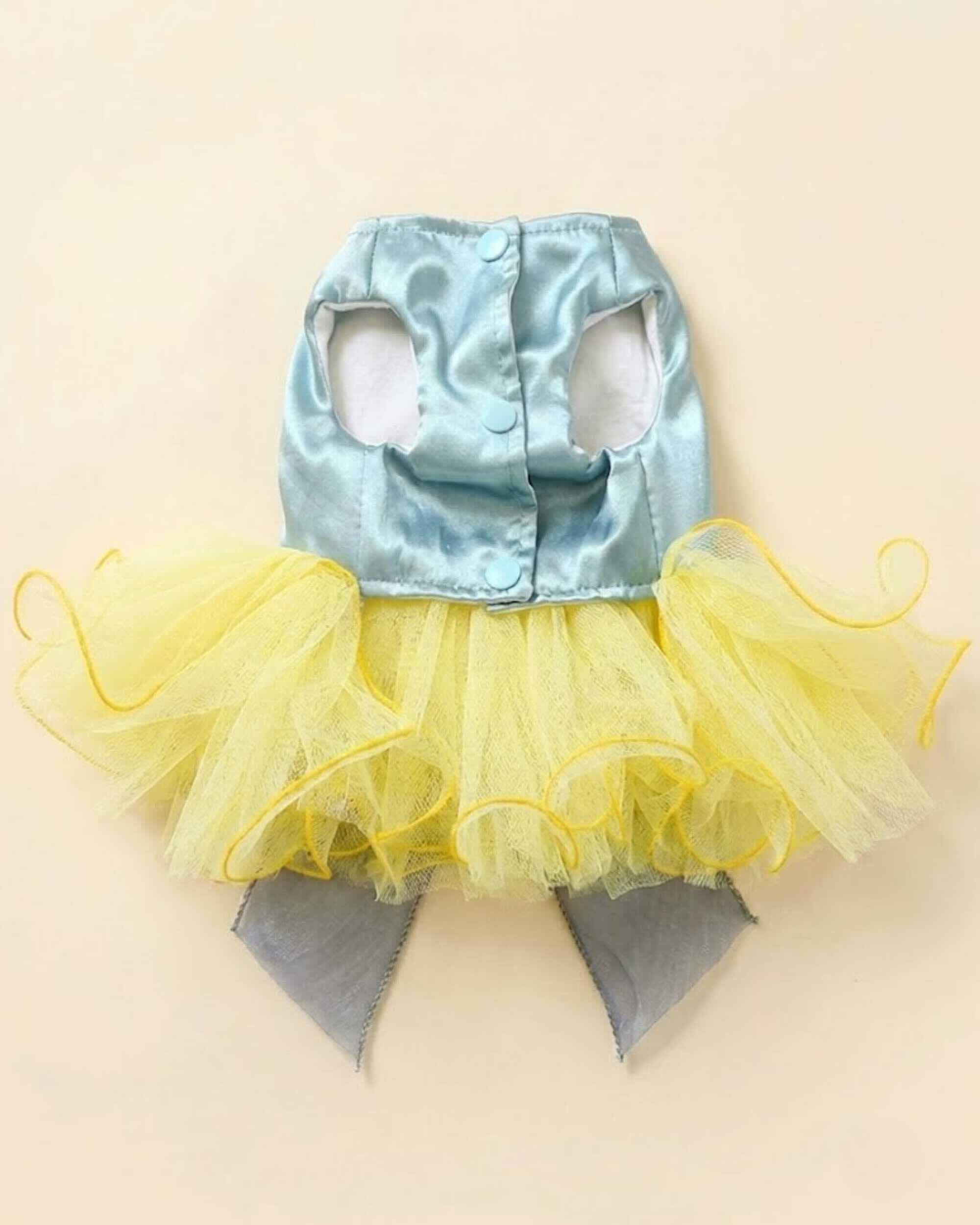 Flat lay of the inside fastening side of an aqua satin pet dress with three snap buttons arm openings and yellow layered tulle skirt