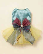 Flat lay of an aqua satin pet dress with yellow tulle skirt and oversized burgundy navy and silver layered bow