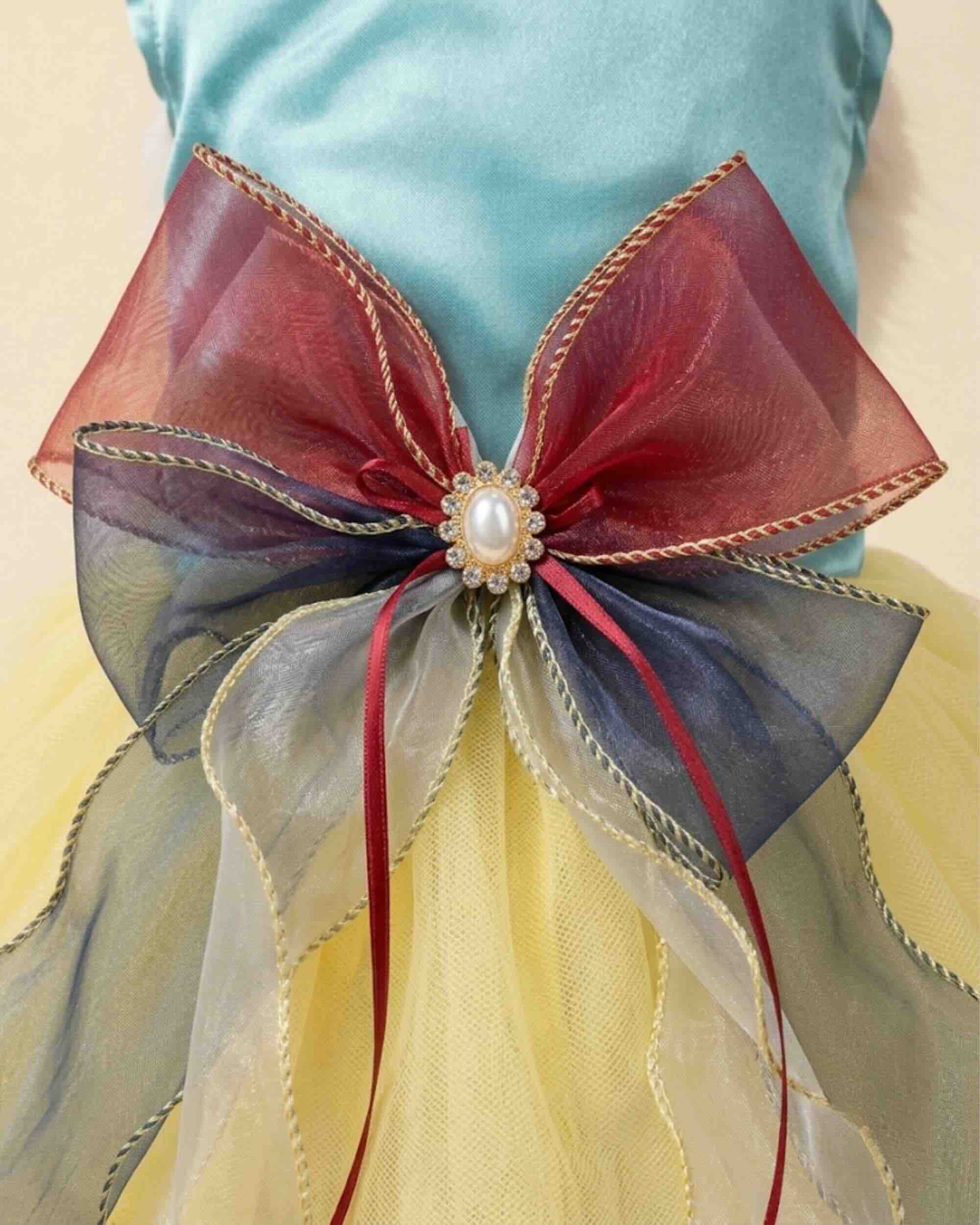 Close-up of the burgundy navy and silver layered organza bow with pearl-style crystal centre on an aqua satin pet dress
