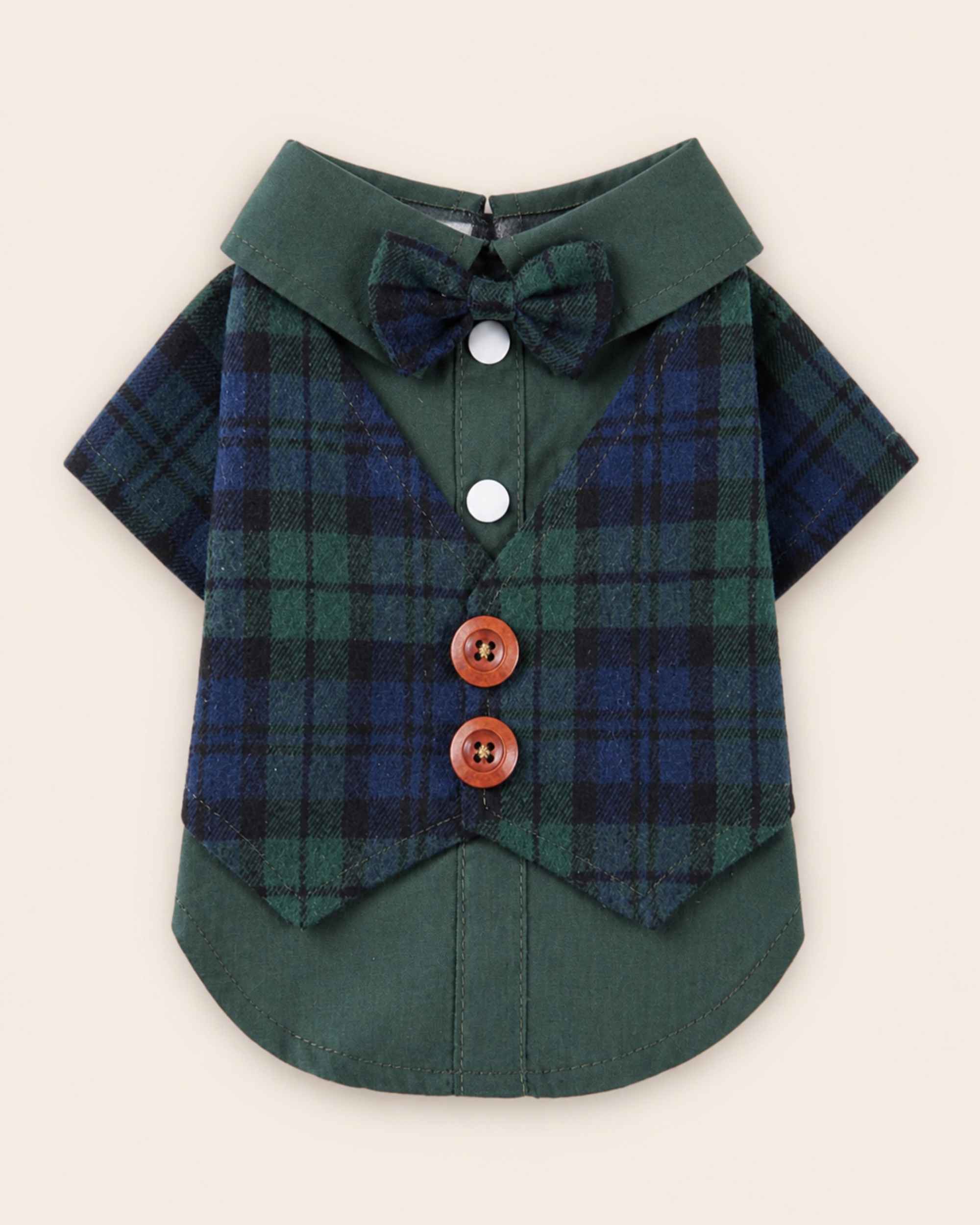 Display-side flat lay of the green and navy plaid pet waistcoat shirt with a matching bow tie, two white snaps, two brown buttons and layered green hem.