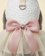 Close-up of the blush pink satin bow, heart-shaped crystal ornament, ivory floral lace bodice and metal D-ring.