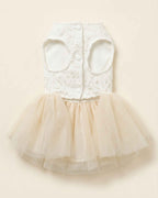 Front closure flat lay of an ivory lace pet dress with two leg openings, three white snap buttons and a layered ivory tulle skirt.