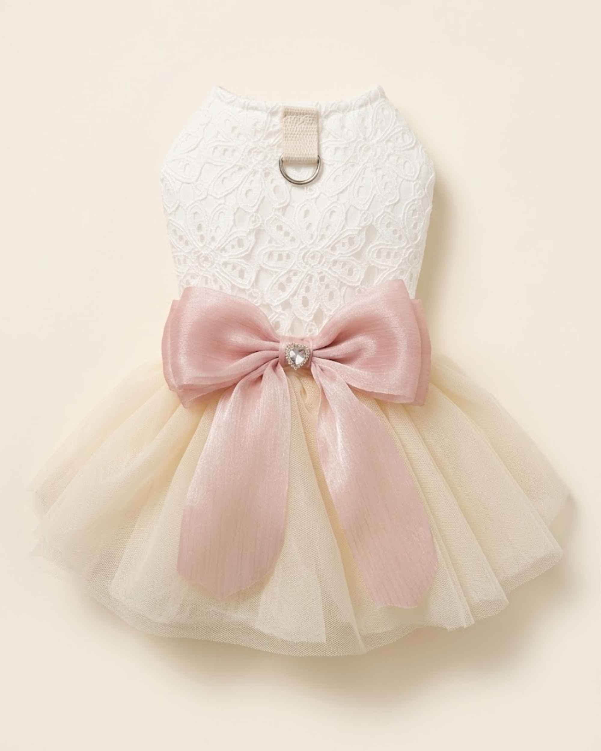 Back flat lay of an ivory lace pet dress featuring a blush pink bow, heart-shaped crystal centre, D-ring and layered tulle skirt.