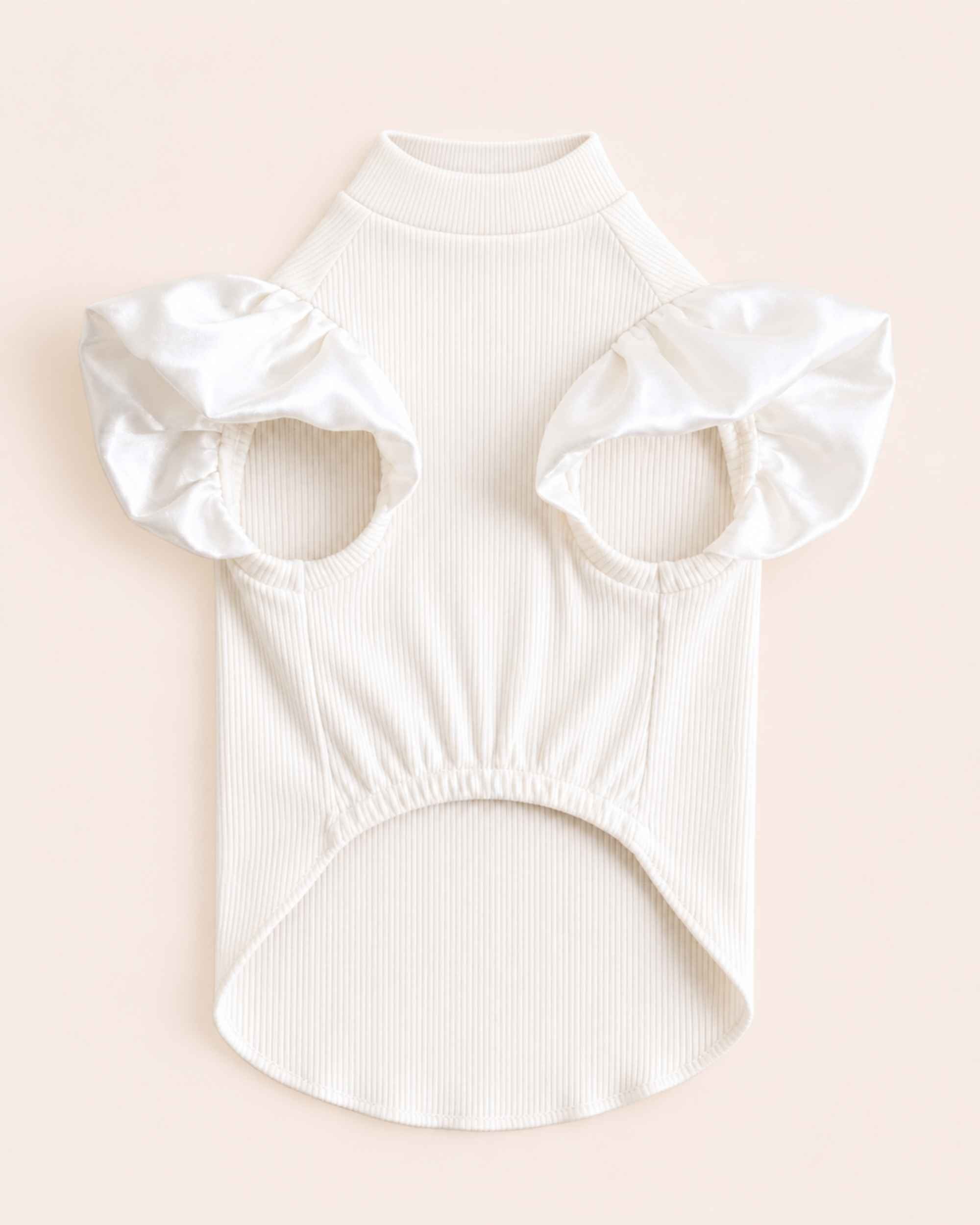 Chest-side flat lay showing the ivory pet turtleneck’s leg openings, satin ruffles and softly gathered belly panel.