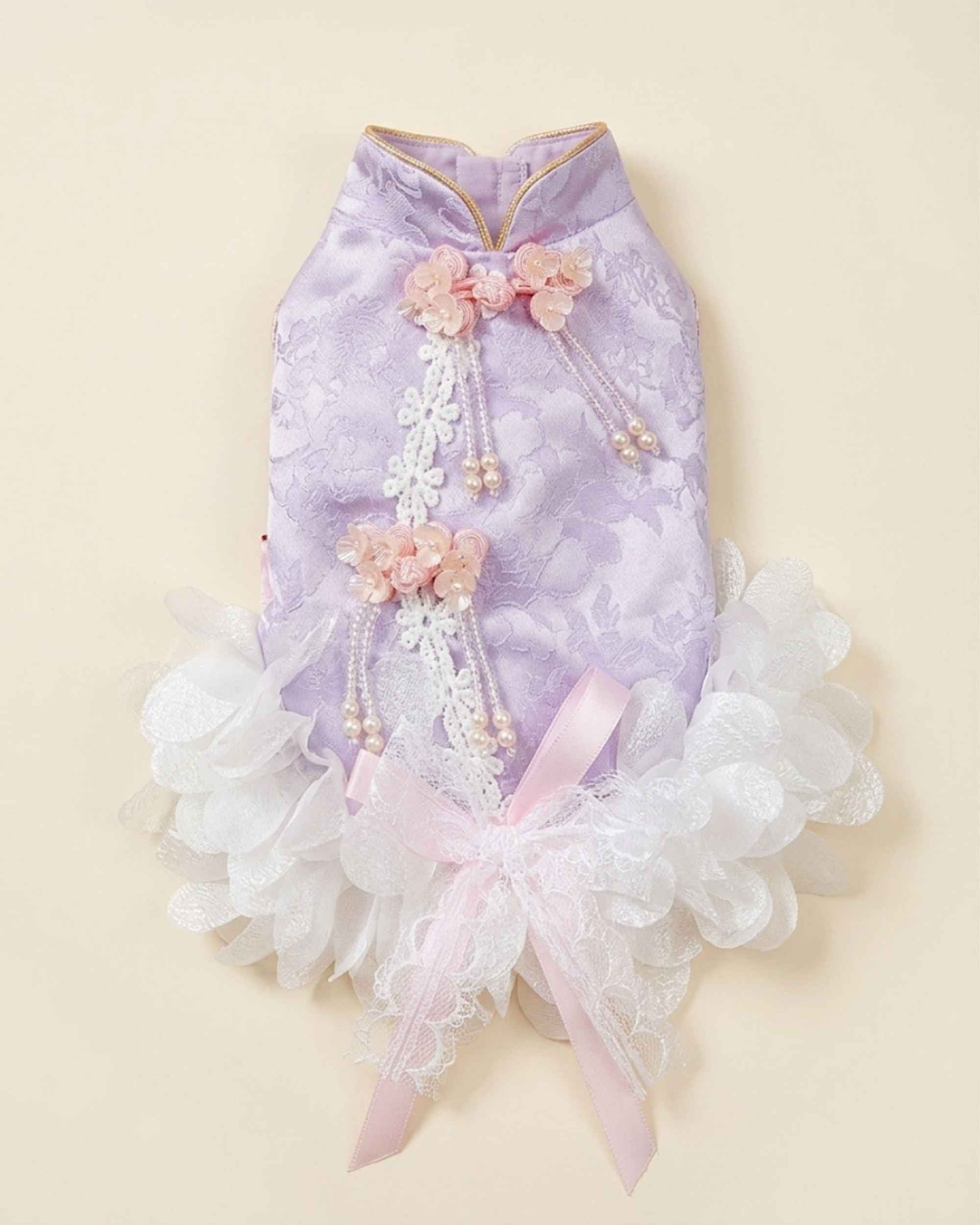 Back flat lay of a lavender jacquard pet dress with pink floral knots, pearl tassels, white lace appliqué and a pink lace bow.