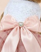 Close-up of the pink satin bow, pearl-trimmed heart jewel, white lace bodice and glitter heart tulle