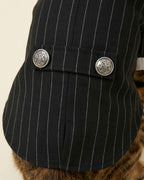 Close-up of the black pinstripe fabric, centre back seam and two embossed silver-tone buttons on the decorative rear tab